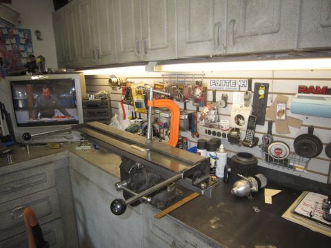 2008 Jeep Wrangler - A cluttered workbench is set up with tools, parts, and a television displaying a man at a desk.