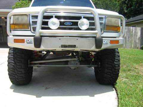 1992 Ford Bronco - The front grille and headlights of a 1992 Ford Bronco are visible, equipped with a protective bull bar and off-road tires.