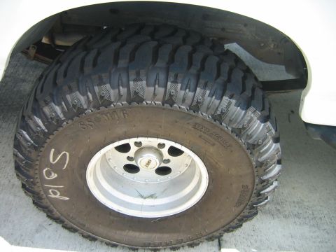 1992 Ford Bronco - A close-up view of a large, aggressive off-road tire mounted on a silver wheel, with the word "Sold" scrawled on the sidewall.