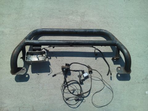1979 Ford F-150 - A black metal pushbar with wiring and a light housing is displayed on a concrete surface.