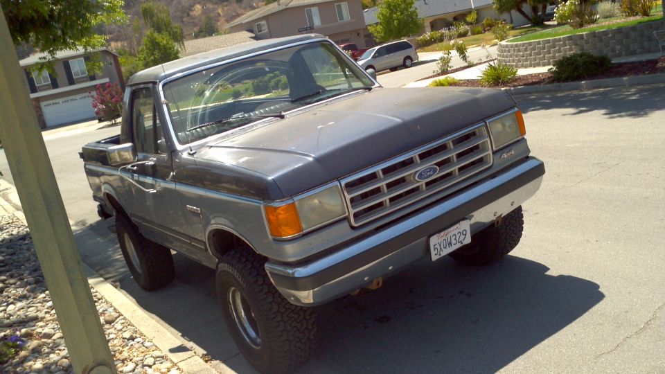 1987 Ford F-150 pickup truck, gray and blue two-tone paint, lifted suspension