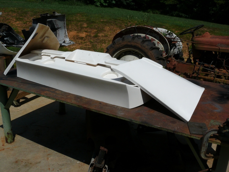 white foam mold for car part on table, old tractor in background