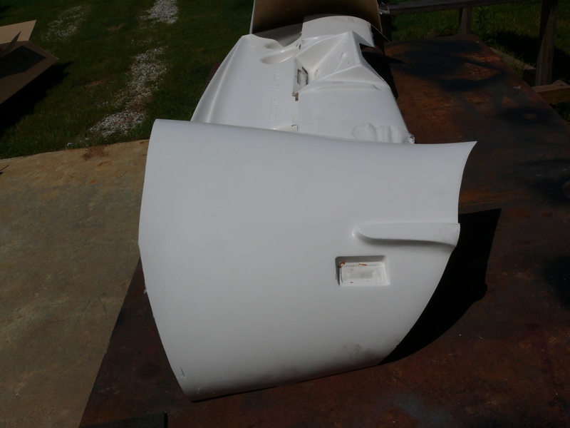 White car fender section with rectangular cutout, on a wooden surface