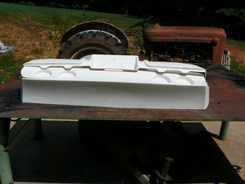 1976 Chevrolet Corvette - A white car part sits on a table in front of a rusty tractor.