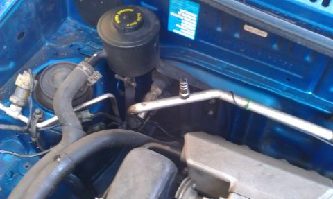 1991 Ford Festiva - Close-up view of the engine bay, showing the power steering fluid reservoir and air conditioning lines.