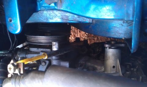 1991 Ford Festiva - Close-up of an engine part with a blue housing and a yellow wire, showing a ribbed pulley.