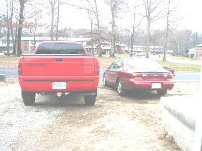 1997 Ford Taurus - Two vehicles, a Dodge pickup and a sedan, are parked outside on a cloudy day.