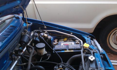 1991 Ford Festiva - Engine bay view of a blue 1991 Ford Festiva, highlighting the battery and other components.