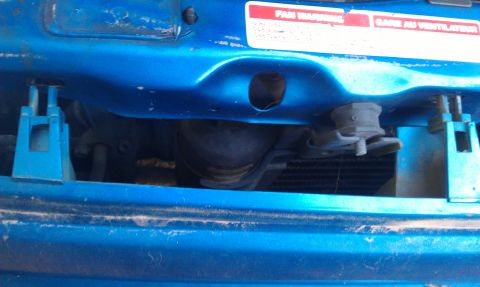 1991 Ford Festiva - Close-up of a blue car's front bumper area, showing a fan warning sticker and mounting brackets.