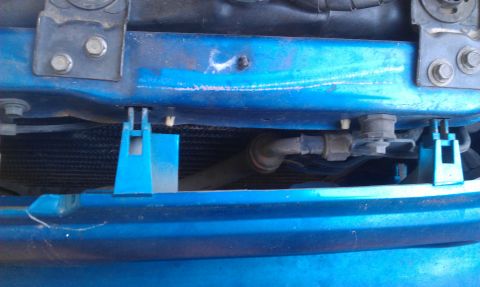 1991 Ford Festiva - Close-up view of a car's radiator and associated hoses, with blue painted metal supports visible.
