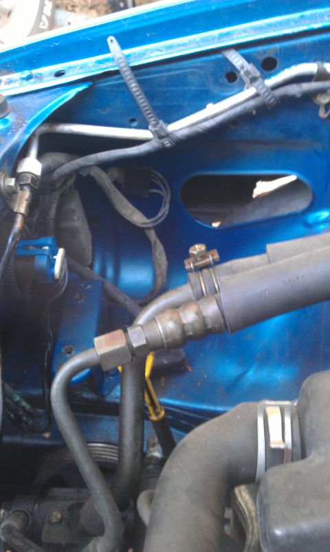 1991 Ford Festiva - A close-up view of hoses and wiring within a blue vehicle's engine bay.