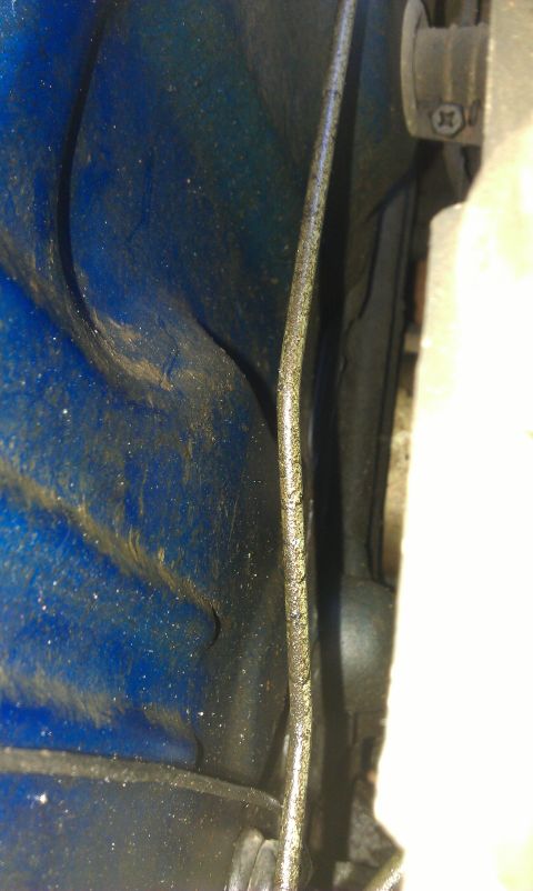 1991 Ford Festiva - Close-up view of a blue painted metal panel with a cable attached.