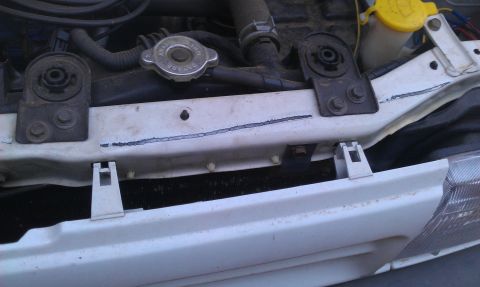 1991 Ford Festiva - Close-up of a white radiator support with a blue line marking and the SuperMotors logo visible at the bottom right.