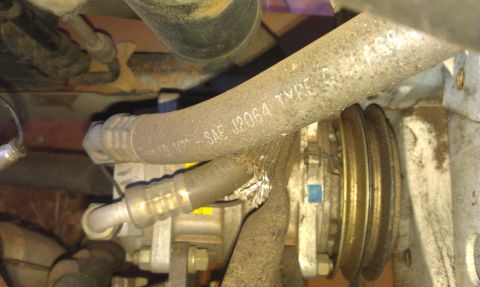 1991 Ford Festiva - Close-up of an air conditioning compressor and hoses, showing part markings.