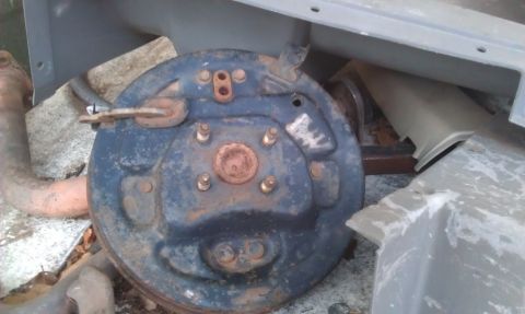 1991 Ford Festiva - A close-up view of a rusty brake drum assembly, possibly from a vehicle, with a fragment of an exhaust pipe visible.