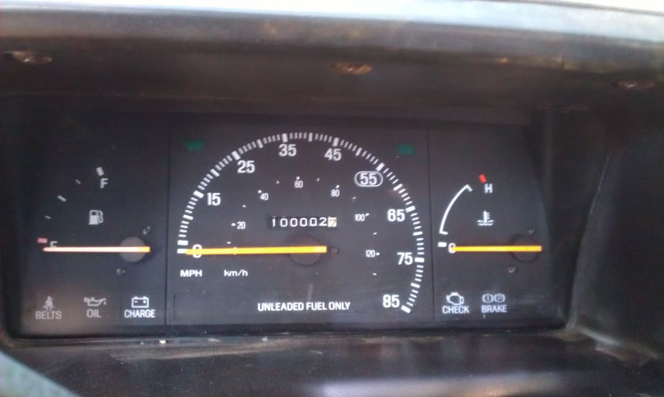 Speedometer reads 100,000 miles, fuel gauge is low, temperature gauge is normal