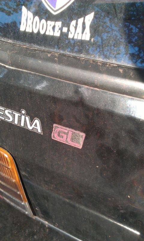 1991 Ford Festiva - Close-up of the rear of a Ford Festiva, showing the GL trim badge and a custom sticker.