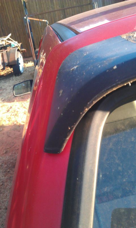 1991 Ford Festiva - Close-up view of the side panel and fender flare on a red vehicle.