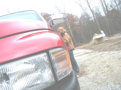 1997 Ford Taurus - A person leans against a red pickup truck with a construction site in the background.