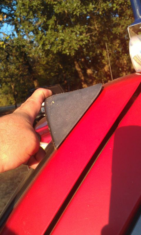 1991 Ford Festiva - Close-up of a red car's exterior trim piece being held by a hand.