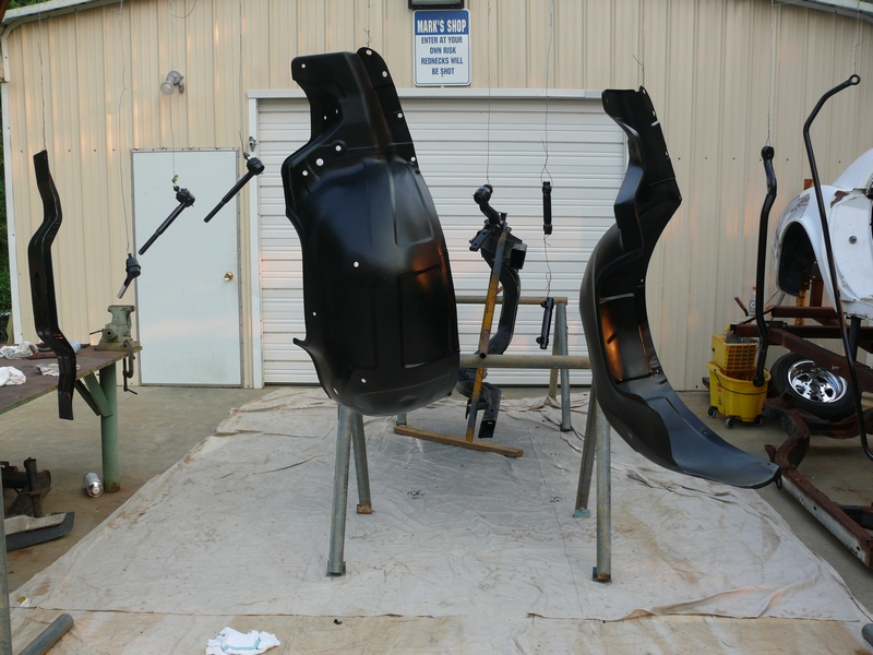 Black painted car fender and other parts hanging for drying