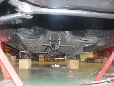 1968 Chevrolet Camaro - The underside of a 1968 Chevrolet Camaro is visible, supported by jack stands and wooden blocks.