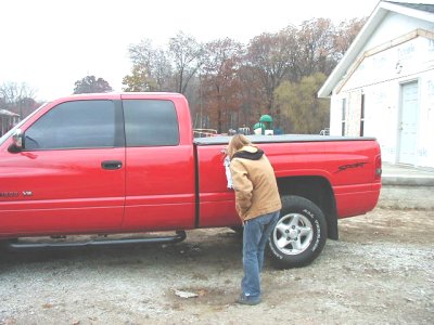 1997 Ford Taurus - A red pickup truck is parked outside a building while a person inspects its side.