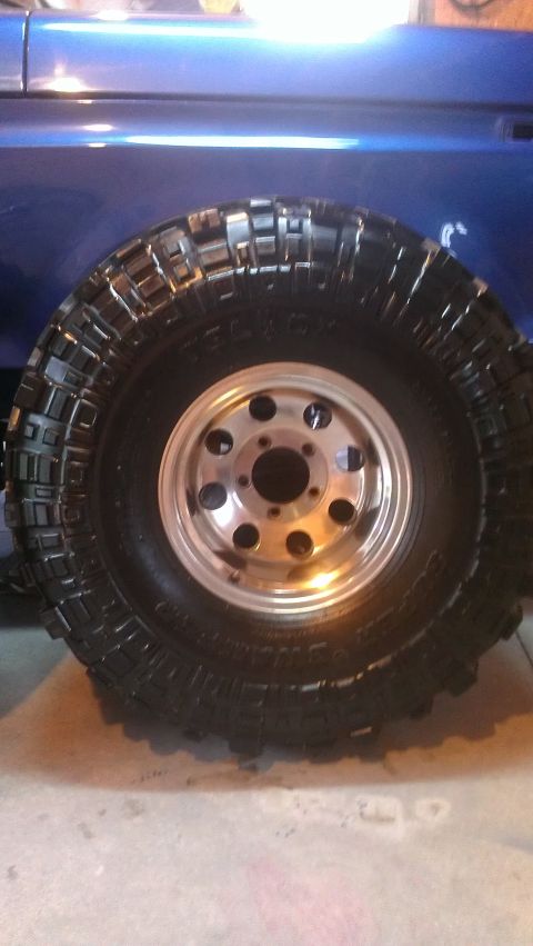 1978 Ford Bronco - A close-up view of a off-road tire and wheel assembly on a blue vehicle.