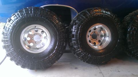 1978 Ford Bronco - Close-up view of two large off-road tires and rims mounted on a blue vehicle.