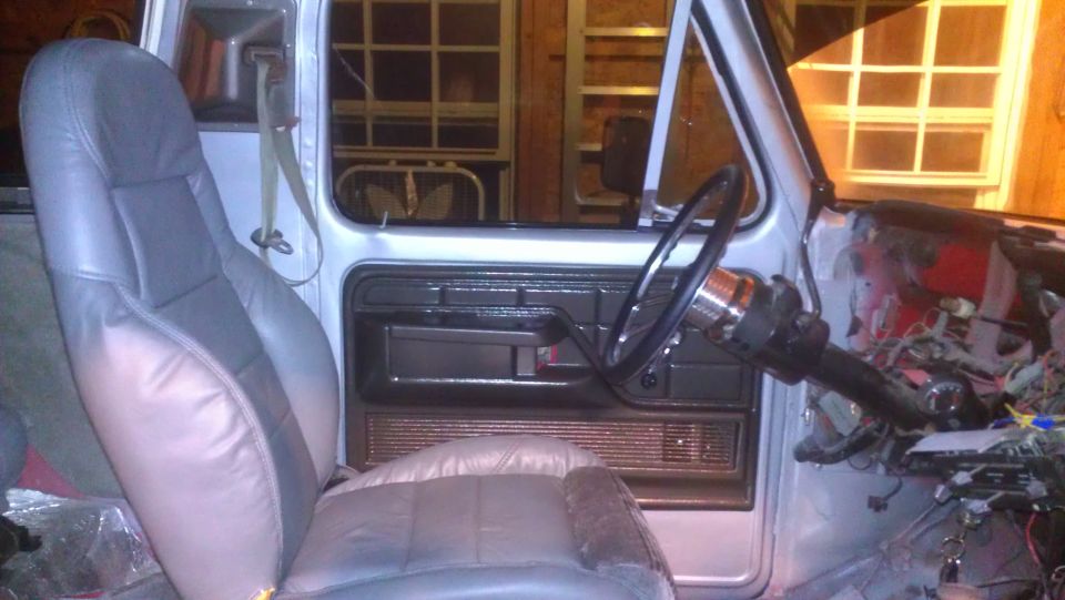 Vehicle interior with gray leather seats, exposed wiring, and a steering wheel