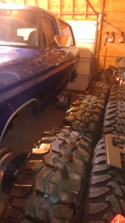 1978 Ford Bronco - A 1978 Ford Bronco parked indoors next to several large off-road tires.