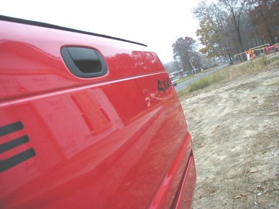 1997 Ford Taurus - Close-up of a red pickup truck's side, showing a '4x4' decal and a reflection on the paint.