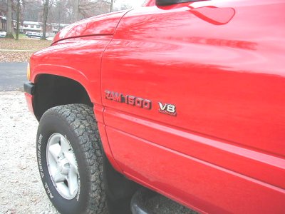 1997 Ford Taurus - Side view of a red pickup truck, identified by its RAM 1500 V8 badging.
