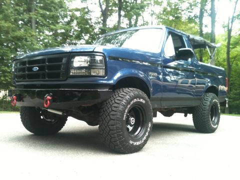 1996 Ford Bronco - This blue 1996 Ford Bronco features an aftermarket bumper and aggressive off-road tires, giving it a stance.