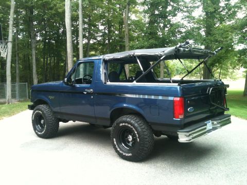 1996 Ford Bronco - This blue 1996 Ford Bronco features a removable soft top, offering an open-air driving experience.