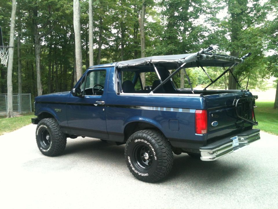 Blue 1996 Ford Bronco with soft top removed, 3q-front view