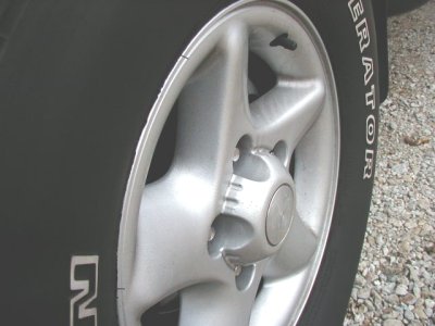 1997 Ford Taurus - Close-up of a silver 5-spoke wheel and tire with visible text on the sidewall.