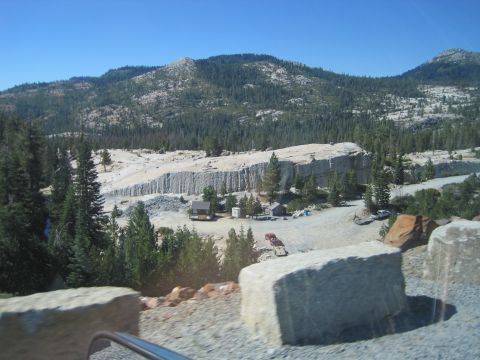 1989 Ford Bronco - A scenic view of a quarry site in a mountainous region with scattered buildings and vehicles.
