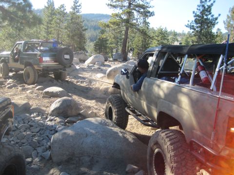 1989 Ford Bronco - Two off-road SUVs navigate a challenging rocky terrain, with one vehicle appearing to tow the other.