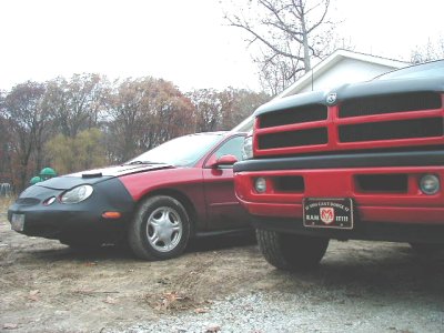 1997 Ford Taurus - A red 1997 Ford Taurus is parked next to a red Dodge Ram truck.