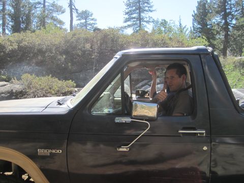1989 Ford Bronco - A man gives a thumbs up from the driver's seat of a Ford Bronco, parked outdoors.