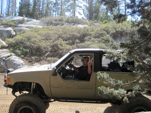 1989 Ford Bronco - A driver in a modified pickup truck navigates a rocky, wooded trail.
