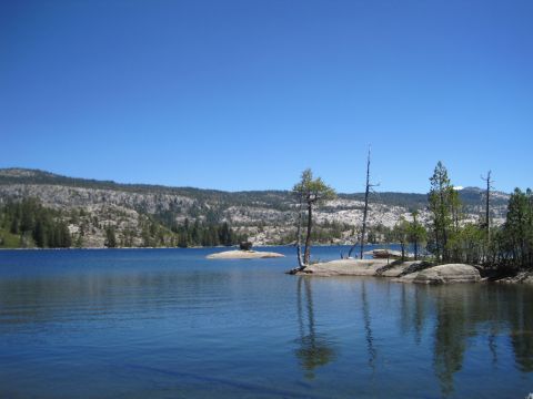 1989 Ford Bronco - A scenic view of a lake surrounded by hills and trees on a bright, clear day.