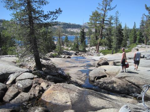 1989 Ford Bronco - A scenic view of a lake surrounded by trees and rocky terrain, with two people enjoying the outdoors.