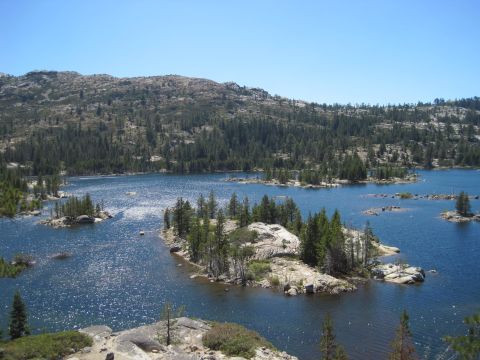 1989 Ford Bronco - A scenic view of a mountain lake dotted with small islands and surrounded by dense pine forests.