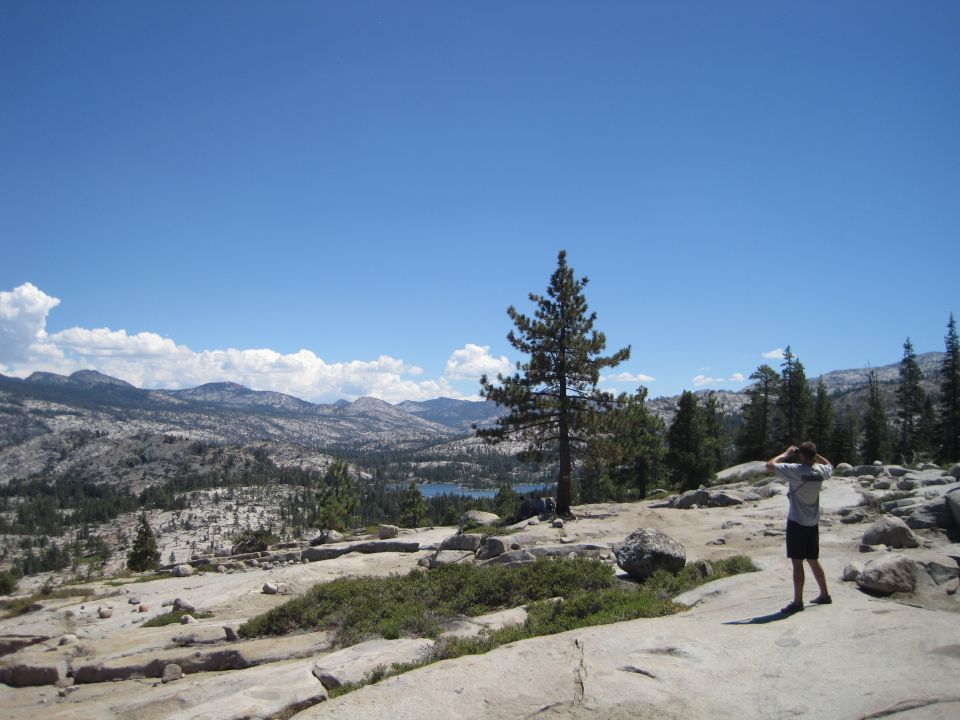 Person on rocky terrain with trees and mountains in background