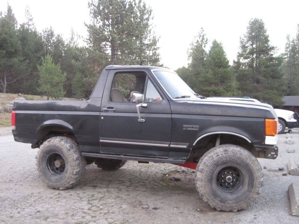 Black Ford Bronco with lifted suspension and large off-road tires parked on a dirt lot