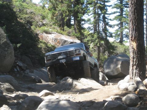1986 Ford Bronco - This 1980s Ford Bronco tackles a challenging off-road course with large rocks and steep inclines.