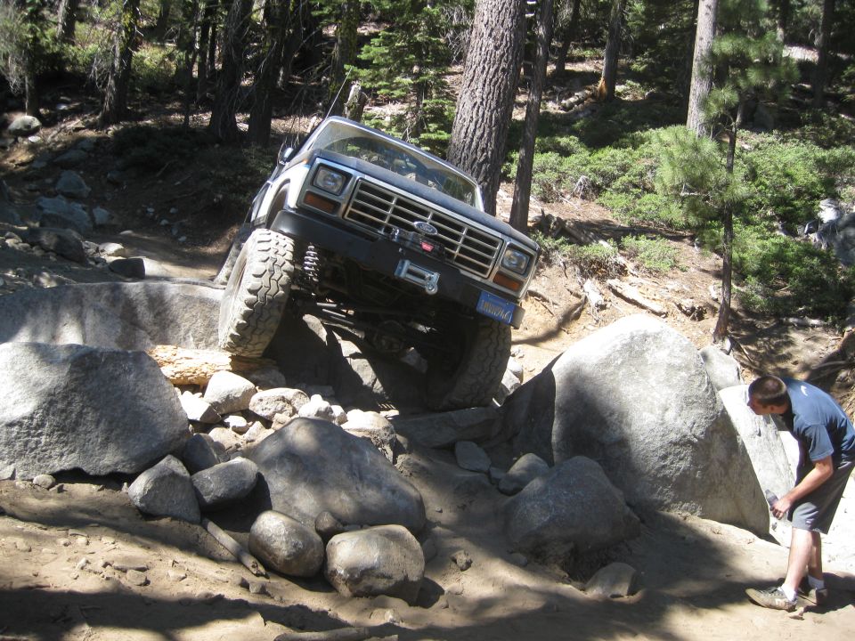 1986 Ford Bronco navigating a steep, rocky trail with large boulders