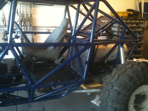 1966 Ford Bronco - Interior view of a custom buggy with a blue roll cage, bucket seat, and a large off-road tire visible.